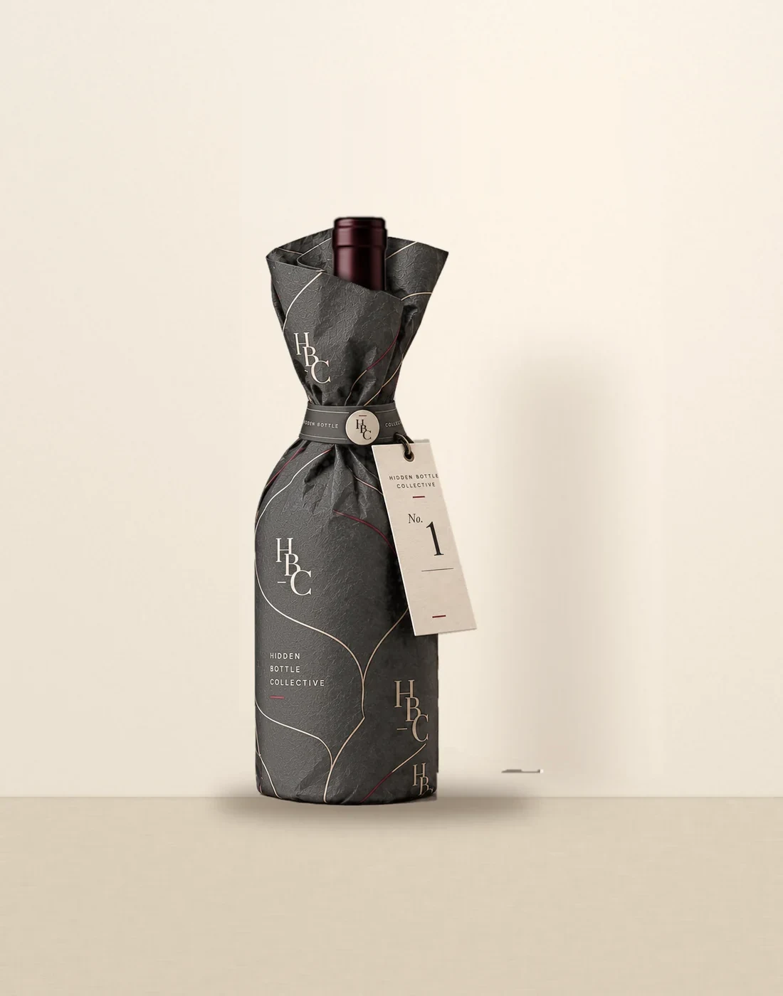 A wine bottle in the graphite Hidden Bottle Collective wrap with its numbered tag, the label hidden